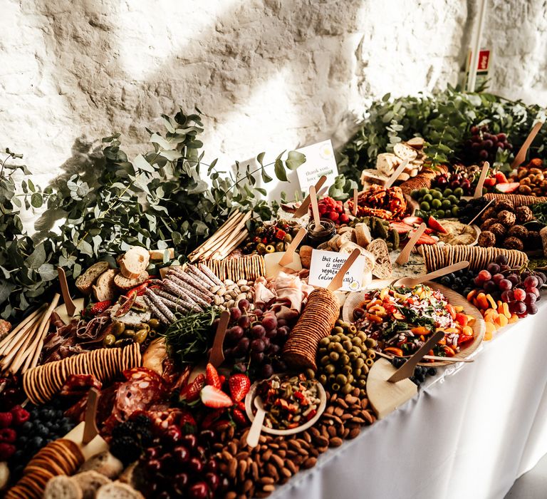 Colourful Spread grazing table complete with olives, meats, cheese, crackers, spreads and eucalyptus leaf decor  