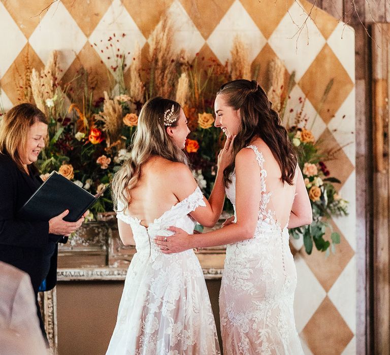 Brides smile at each other and look so in love as they stand at the altar for their wedding 