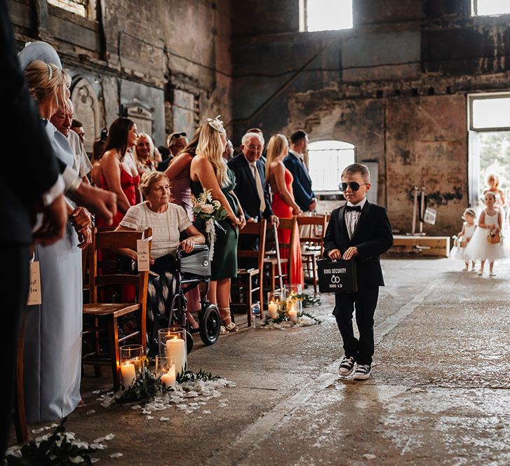 Page boy in black tie and sunglasses walks down the aisle at The Asylum 