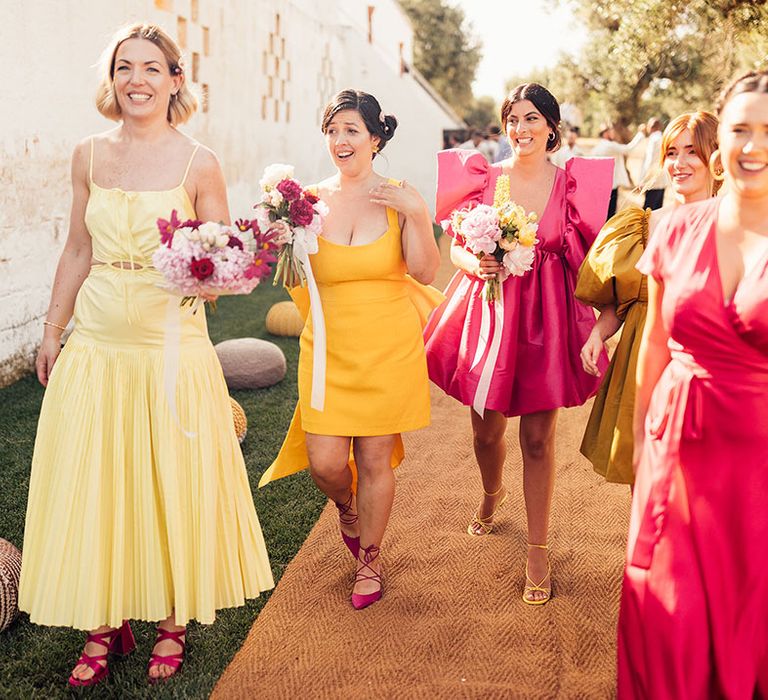 Bridesmaids in bright pink and different shades of yellow bridesmaid dresses