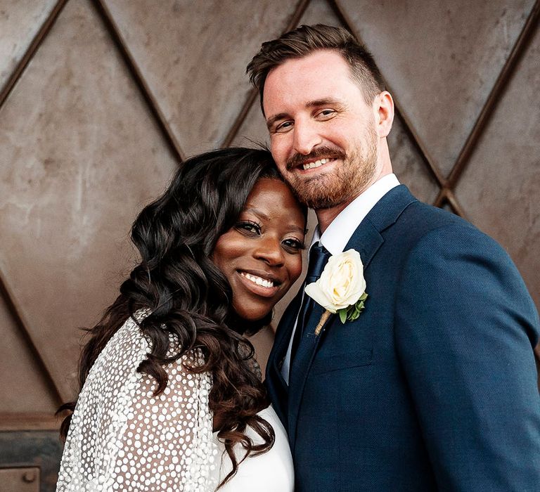 Black bride wears her black hair in loose curls and wears tulle wedding cape with glitter polka dots 