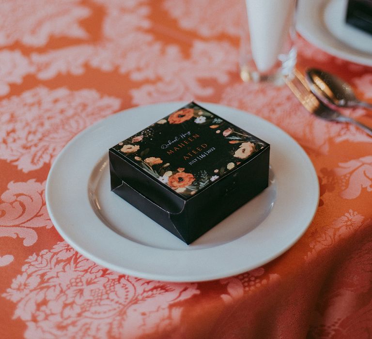 Wedding favour on white plate complete with colourful fabric table covering 