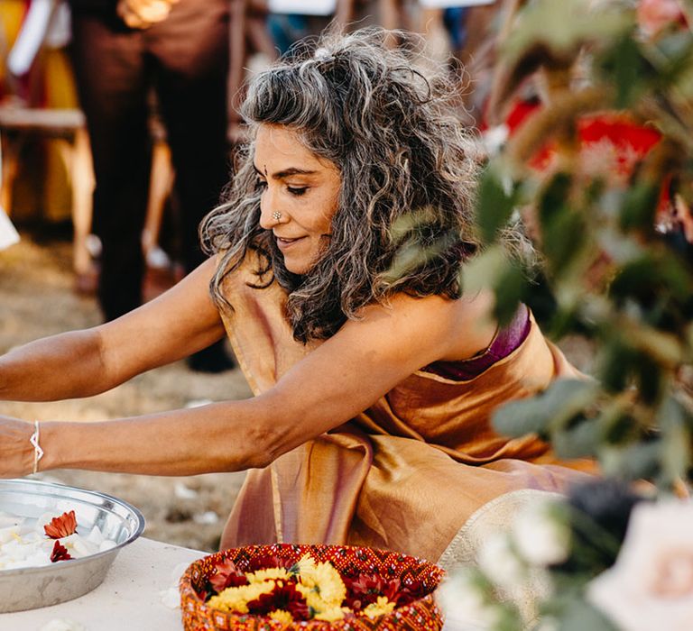 Wedding guest prepares flowers during Indian ceremony 