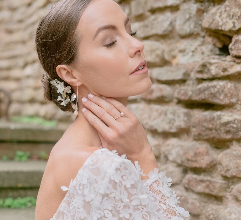 Bride wearing a pearl ring and earrings with a floral hair accessory 