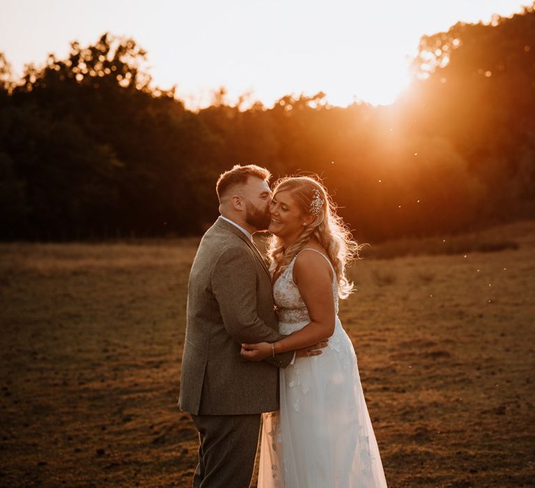 Groom kisses the bride on the cheek during their golden hour portraits 