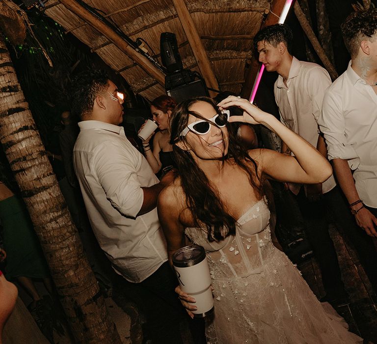 Bride wears sunglasses and parties outdoors during her rave reception celebration