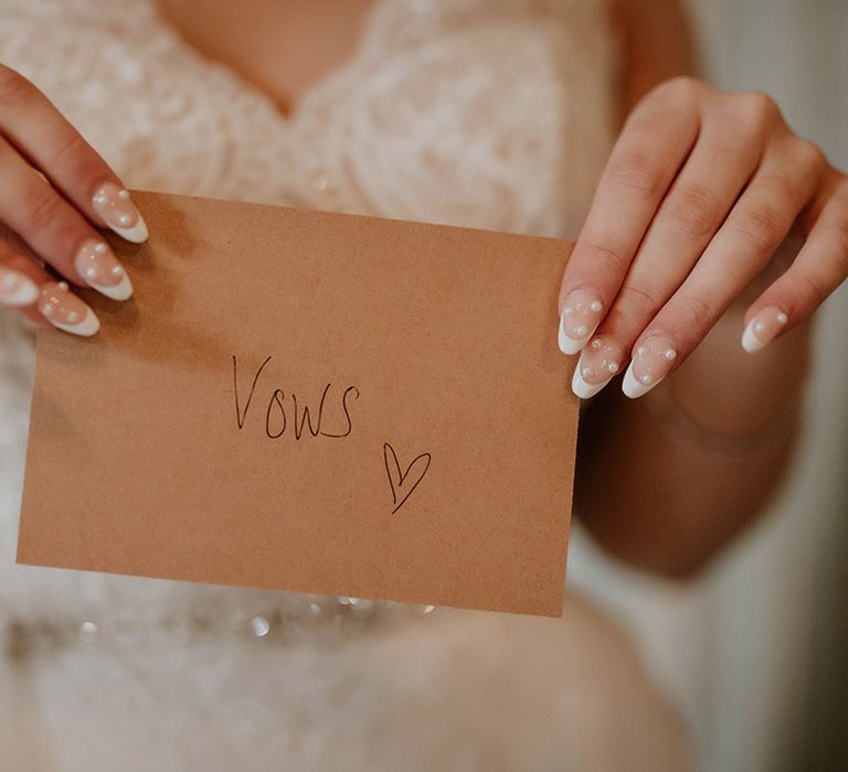 Bride holds up brown envelope containing personal wedding vows 