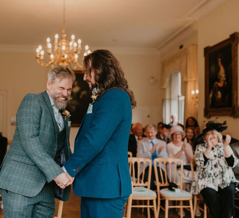 Groom in tartan suit laughs during wedding ceremony 