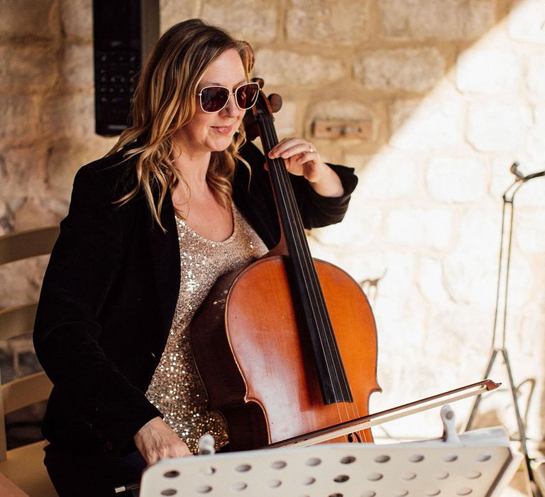 Cello player in sunglasses during wedding ceremony 