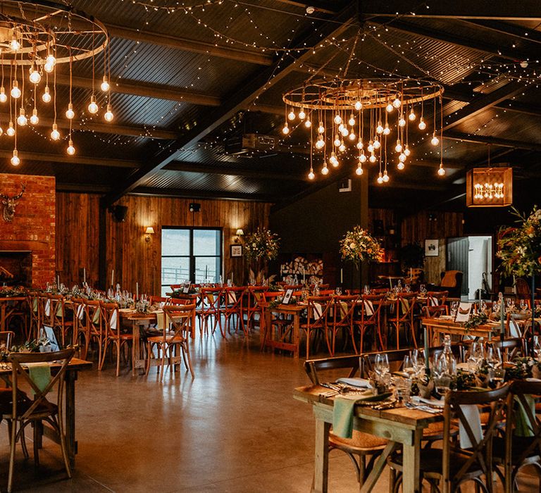 Silchester Farm wedding venue in Hampshire decorated with fairy lights, festoon lights, and a green and white colour scheme with tall table centrepieces on some tables