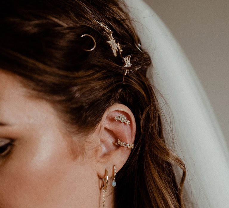 Bride with a curated ear with gold jewellery with floral and star patterns to match her gold hair accessories 