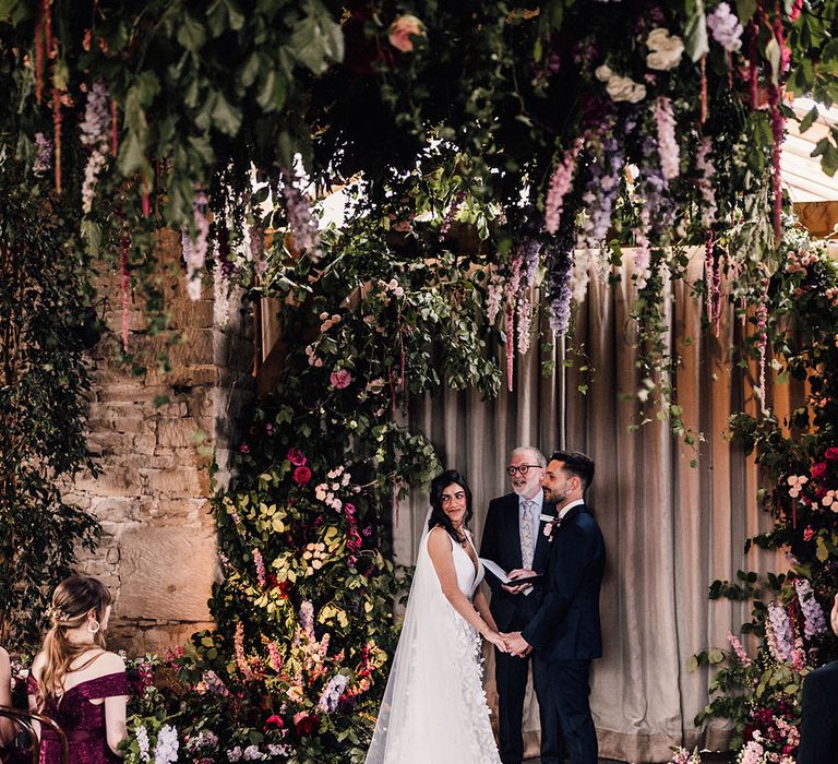 Botanical wedding with huge cascading flowers and wildflowers decorating the aisle and altar at Cripps Barn