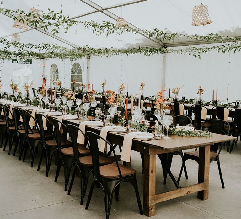 hanging foliage above a reception table decorated with orange and black wedding decor 