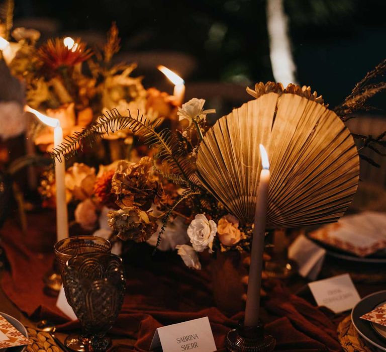 Rustic wedding tablescape with burnt orange dried roses, dried flower and foliage floral centrepieces, light orange tapered candles and burnt orange table runners