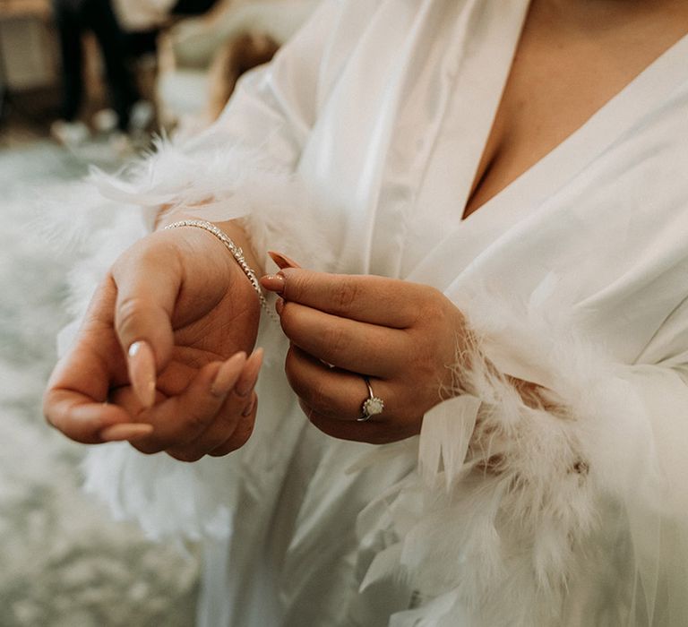 Bride with long neutral wedding nails putting on her diamond tennis bracelet for the wedding 