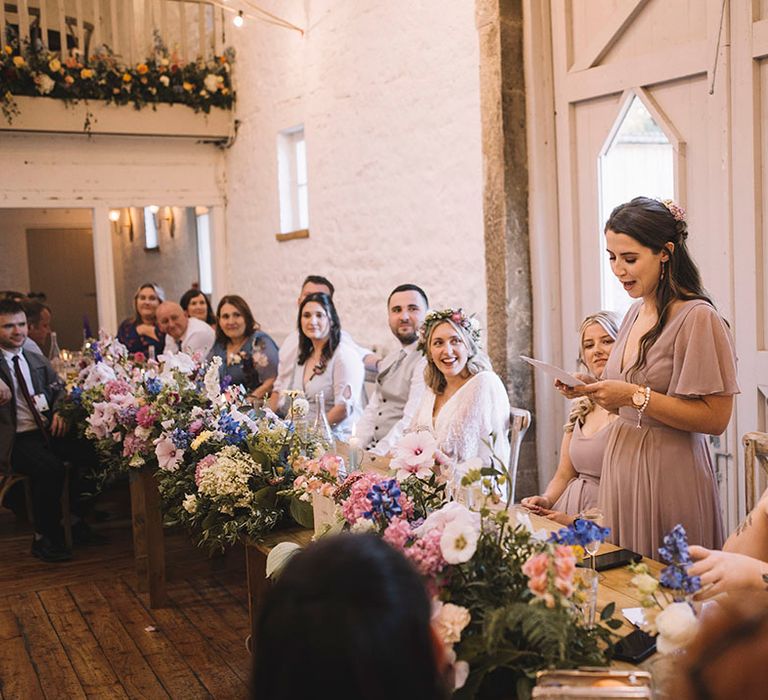 Bridesmaid stands in pink bridesmaid dress to deliver maid of honour wedding speech 