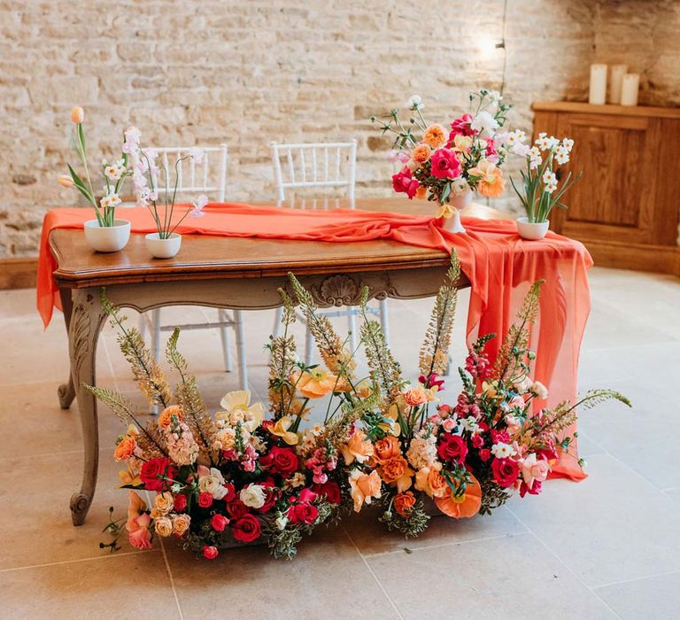 Merriscourt wedding venue reception room with wooden table with orange table runner and mixed seasonal flower arrangements 