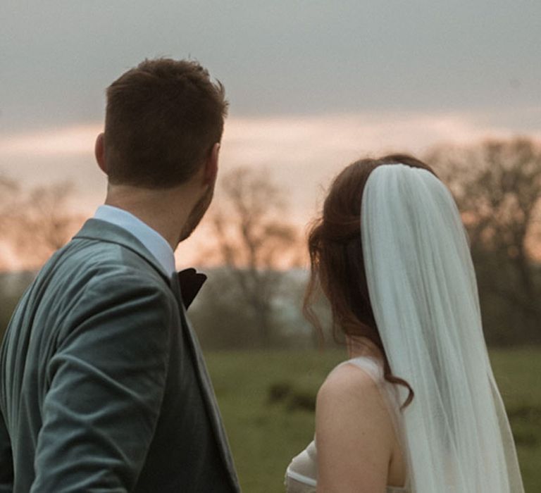 Groom in velvet blazer with bride in sequin corset wedding dress at sunset 