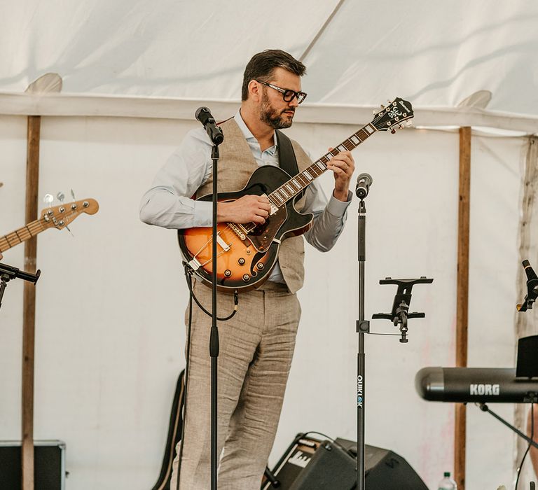 The groom playing guitar at the marquee wedding 