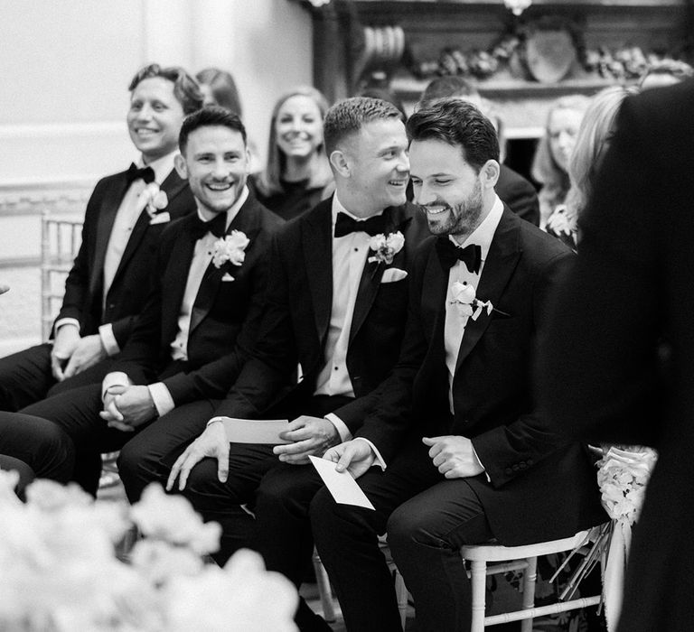 Groomsmen in black tie sit together in the front row for the wedding 