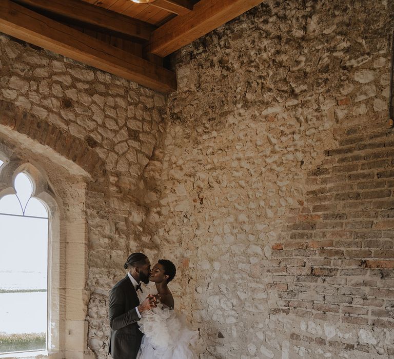 Groom in black tie with bride in statement Millia London wedding dress with long train 