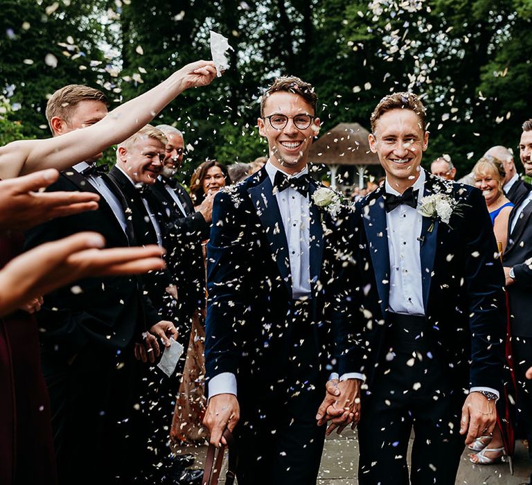 LGBTQI+ wedding with fun confetti moment featuring two grooms in blue tuxedos 