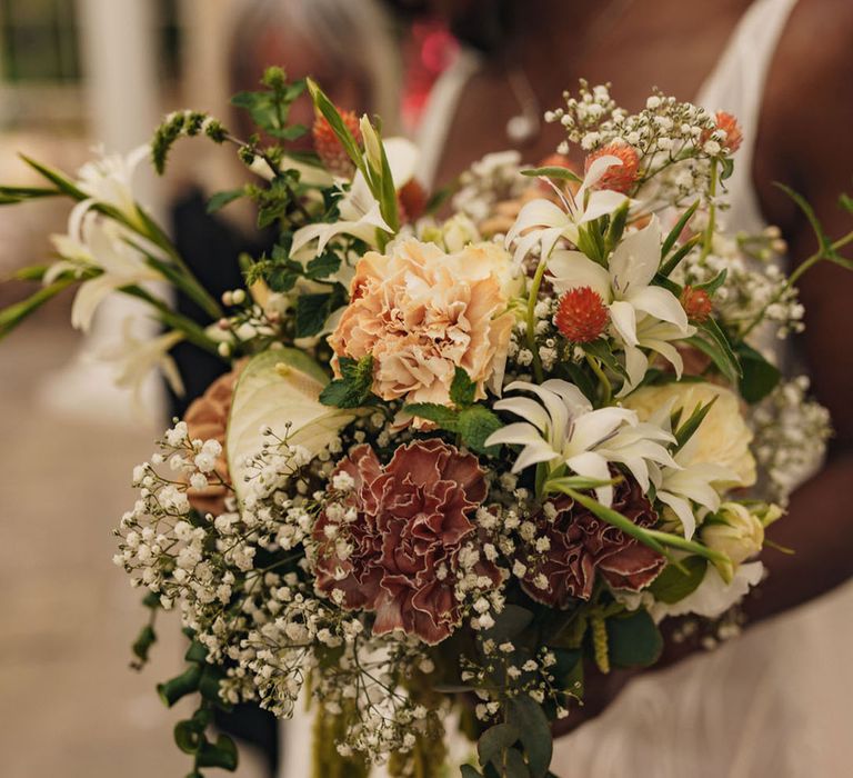 Bride holding neutral wedding bouquet with green hanging amaranthus, roses and more 