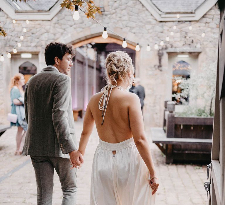 Bride in low back wedding reception dress walking in with the groom at Wyresdale Park 