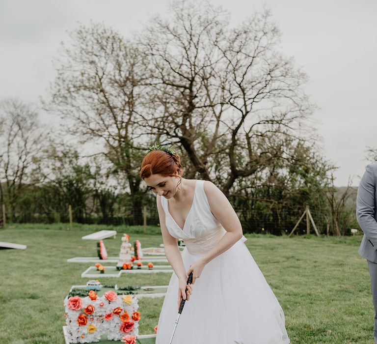 Bride playing mini golf wedding game at Hardwick Moat Weddings outdoor wedding venue in the East Midlands 