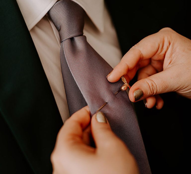 Groom wearing a special gold bumble bee pin on his purple tie 