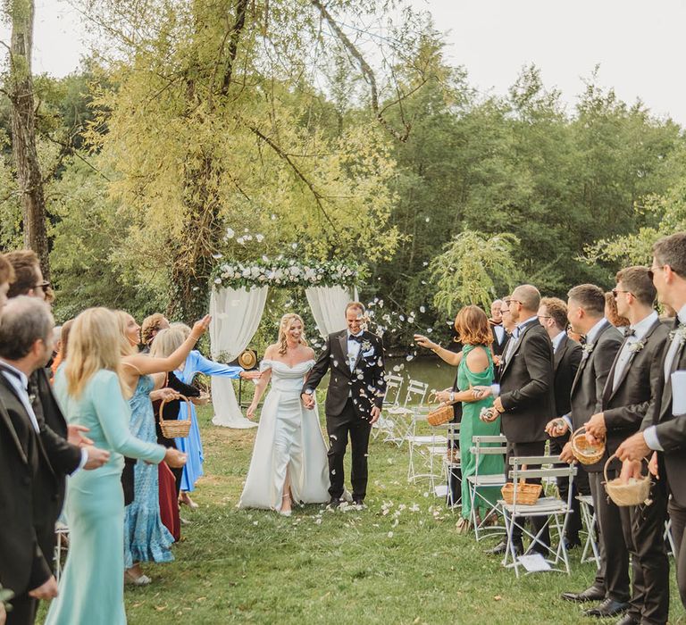 Confetti exit for the bride and groom at outdoor wedding ceremony 