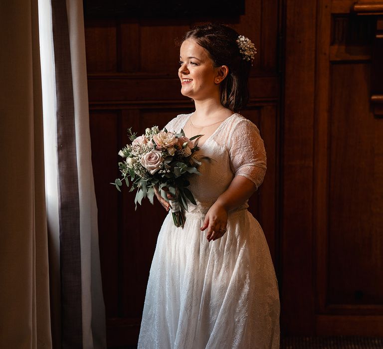 Bride with Achondroplasia in lace wedding dress holding a pink rose bouquet for classic wedding 