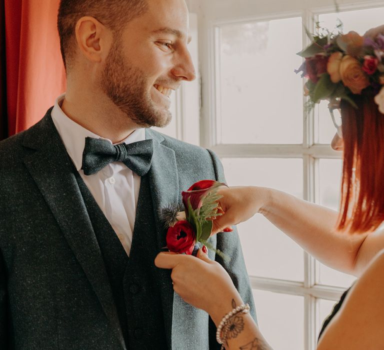 Bridesmaid helping groom with buttonhole for the elopement wedding 