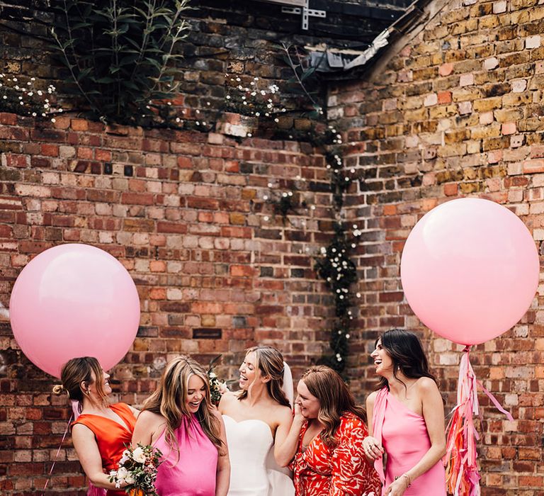 Large pink wedding balloons for photo backdrop with bridal party in pink and orange mismatched bridesmaid dresses 