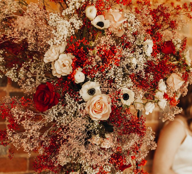 Bride on her wedding day with red floral installation