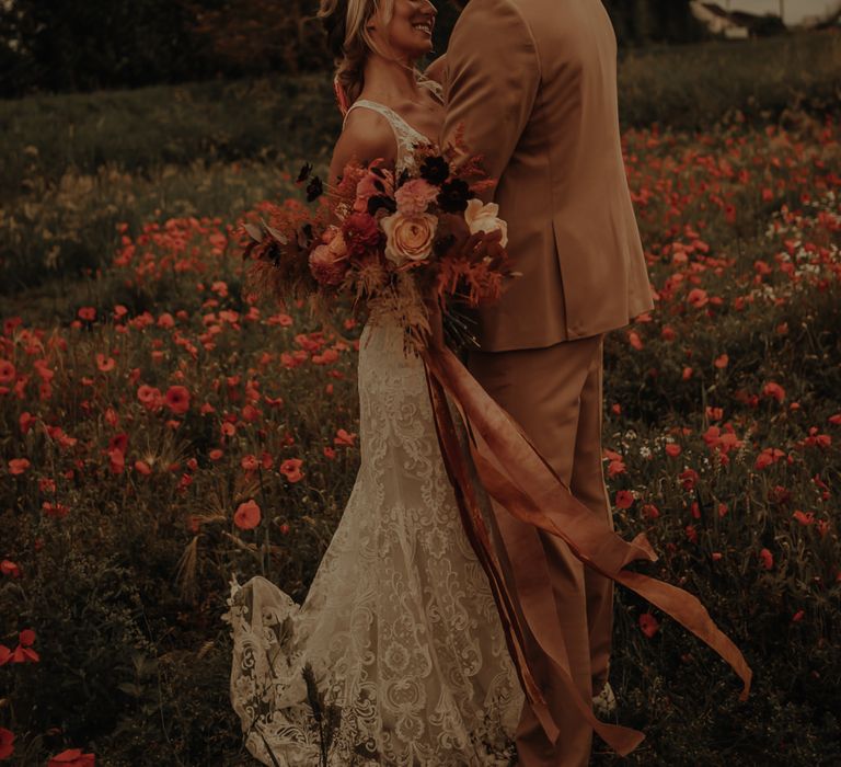 Bride and groom kissing in a poppy field 