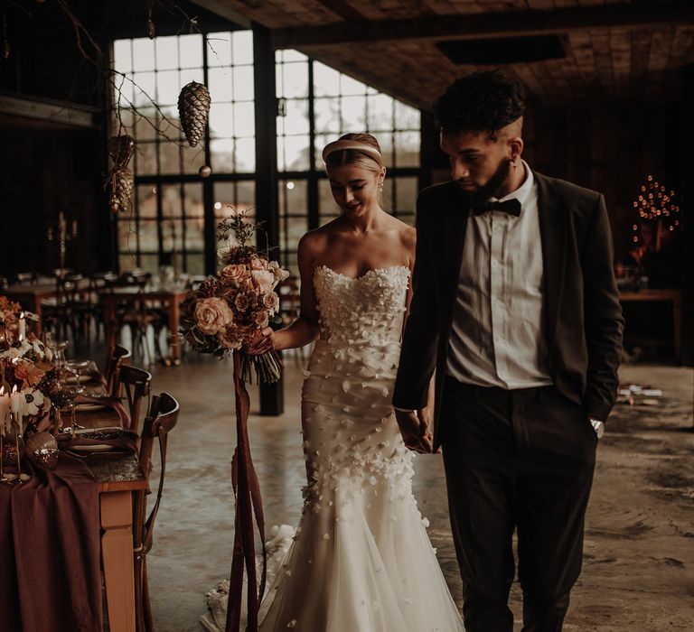 Bride in Emma Beaumont wedding dress and groom in tuxedo walking through their intimate reception at Hidden Cabin Barns 