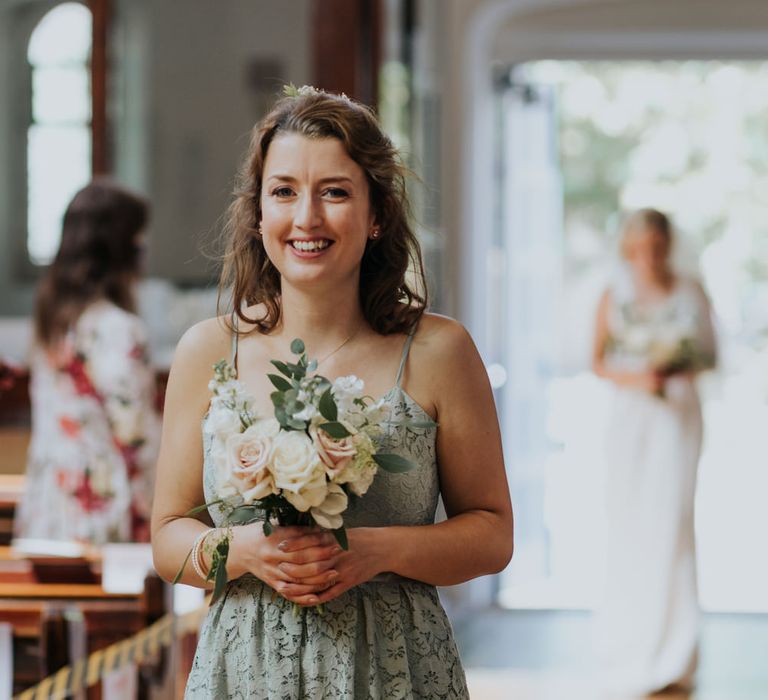 Bridesmaid in lace dress walking down the aisle 