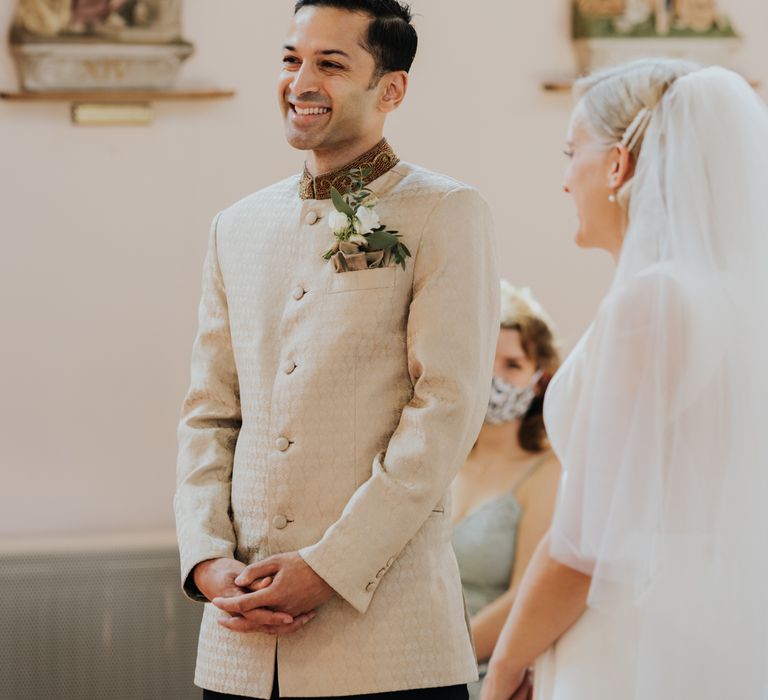 Groom in gold bespoke suit smiling at micro wedding 