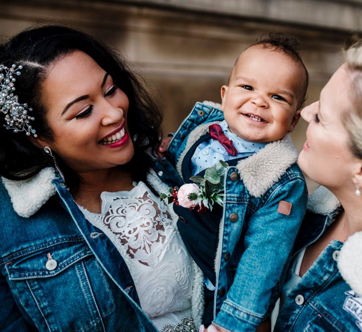 Newly-wed brides on their wedding day with their son and matching denim jackets 