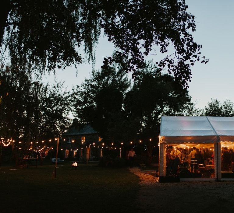 At home marquee reception with festoon lights in the garden 