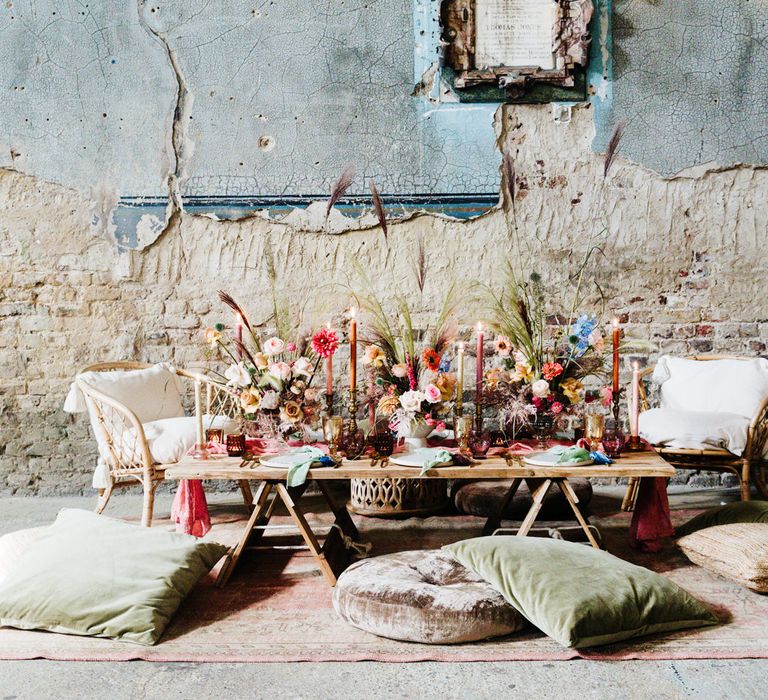 Casual wedding tablescape with rugs, cushions, candles and bright flowers 