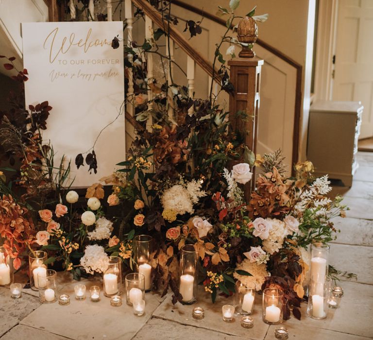 Welcome wedding sign with flower display and candles at Reymerston Hall