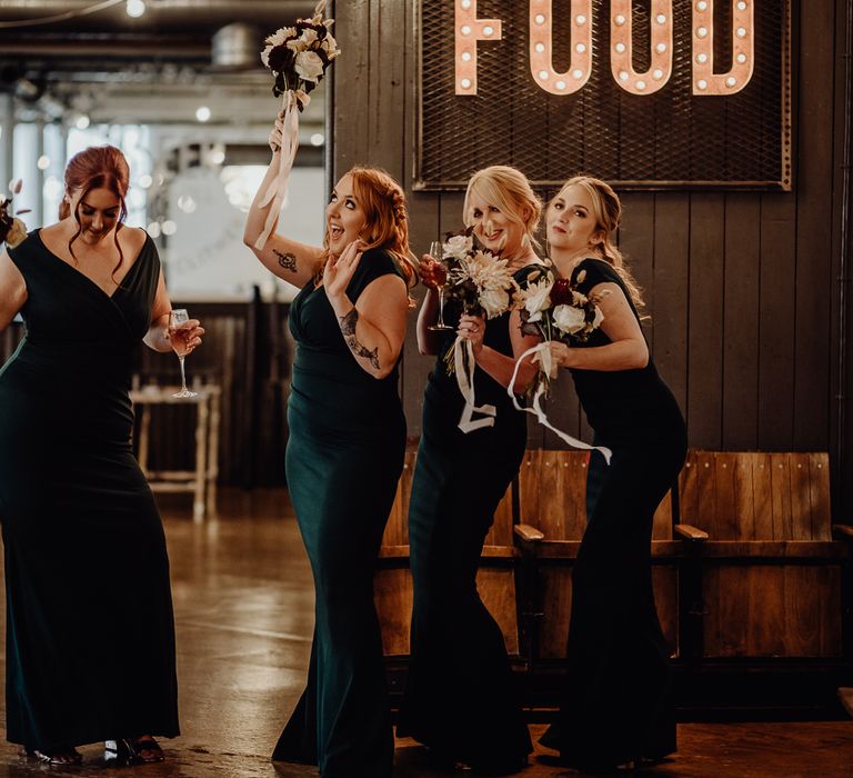 Bridesmaids in deep green off the shoulder dresses with dried flower bouquets 