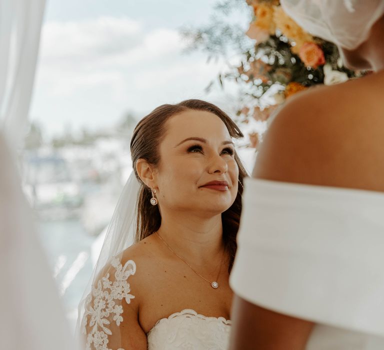 Beautiful bride in a strapless wedding dress and lace edged veil smiling during the wedding ceremony 