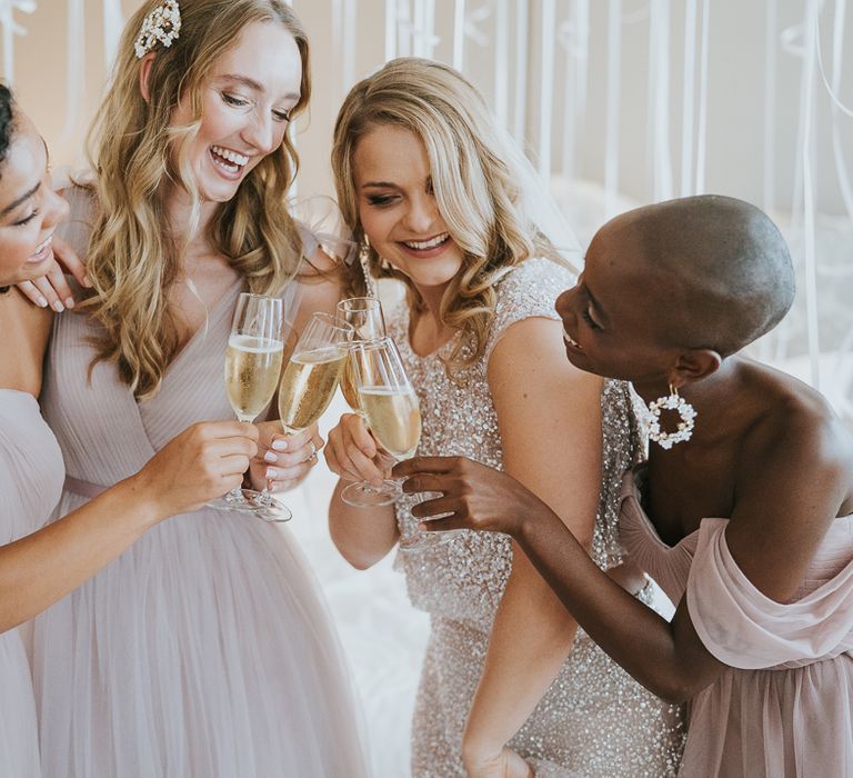 Bridal party sipping champagne on the wedding morning in sparkly and chiffon dresses 