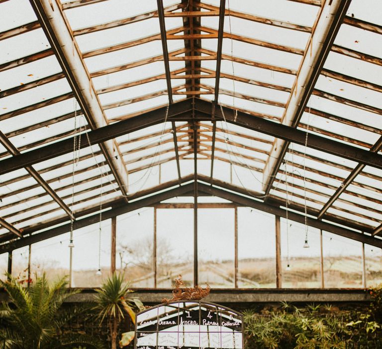 Window pane table plan on a metal easel in the middle of the glasshouse wedding reception 