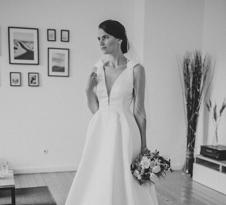 Bride in white full length Jesus Piero wedding gown and veil holds pink and white rose bouquet 