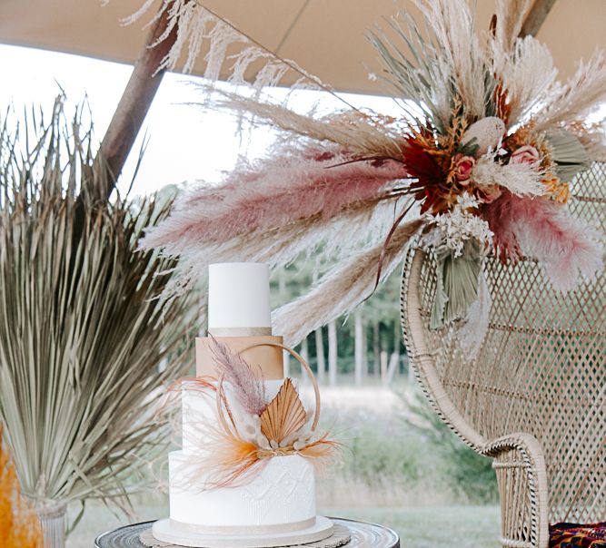 4-tier wedding cake surrounded by large pampas grass and dried floral arrangements