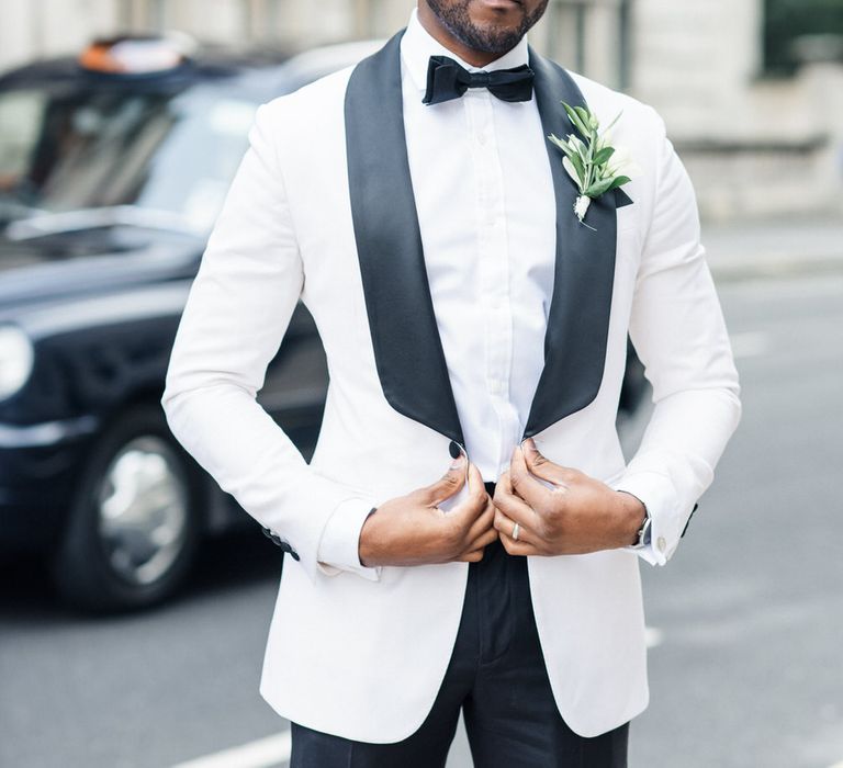 Groom wears black and monochrome tux with white floral buttonhole